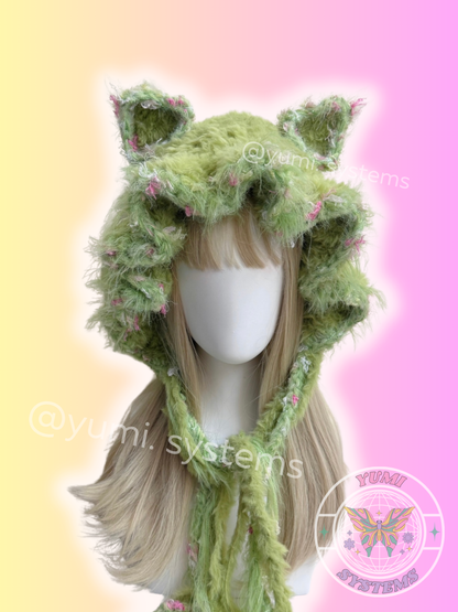 Fuzzy green crochet cat ear beanie with pink speckles on mannequin, Y2K aesthetic fashion accessory close up texture.