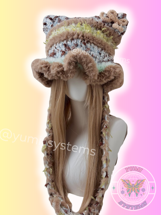 Close-up of heavy-knit handmade cat ear beanie with fuzzy trim and long tassels in black/blue and earthy moss colors.