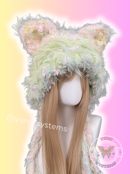 A collection of YUMI SYSTEMS handmade thick plush crochet hats in various colors including moss green, leopard print, pastel lavender, and mint green.