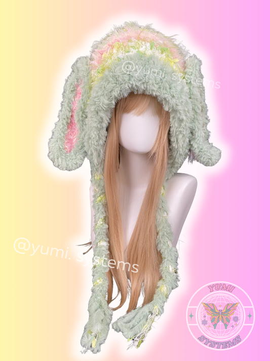YUMI SYSTEMS handmade pastel green and pink plush crochet hat with detachable long bunny ears and pom-poms.